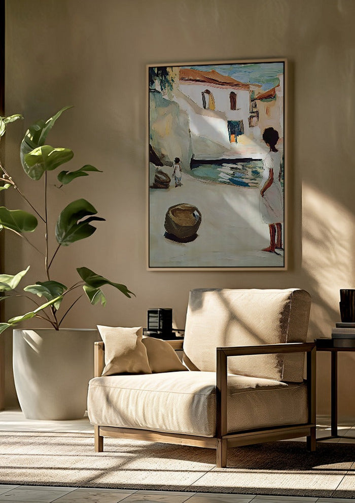 Village Street by Elena Avanesova framed above a beige armchair beside a potted plant