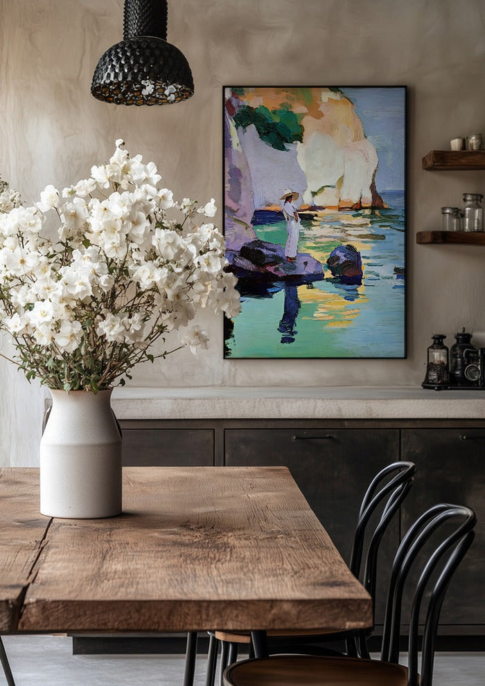 Woman by the Cliffs by Elena Avanesova in a black frame above a rustic table with white flowers
